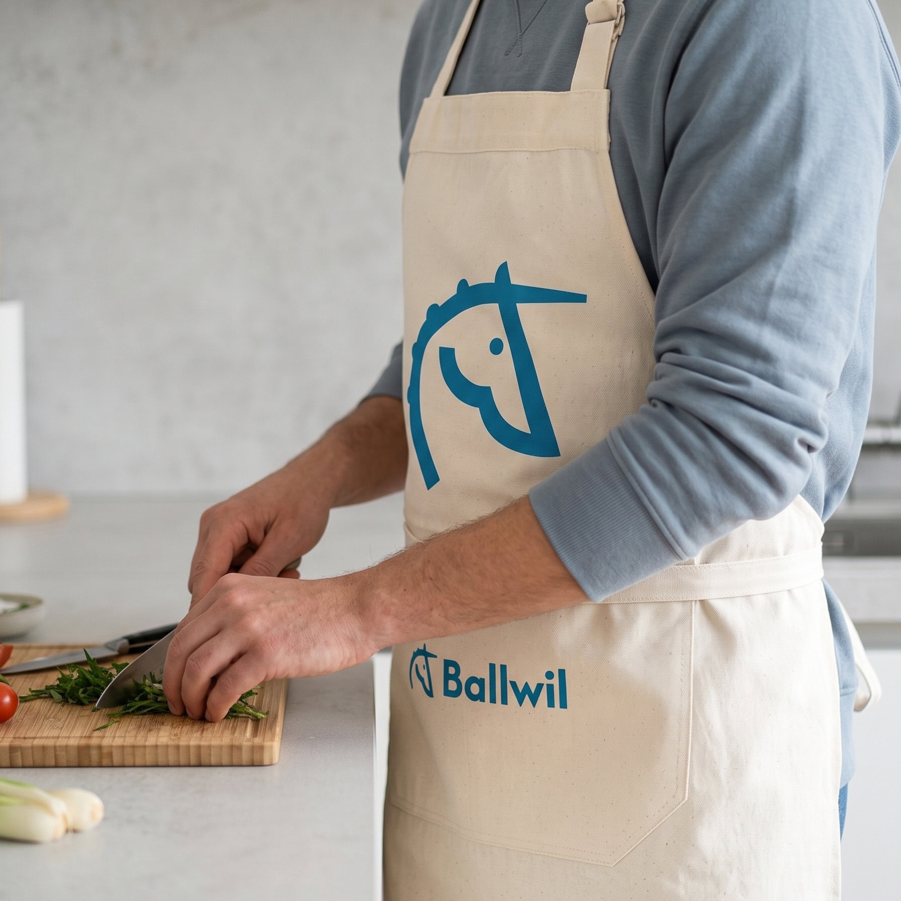 person in küchenschürze mit ballwil-logo beim gemüseschneiden