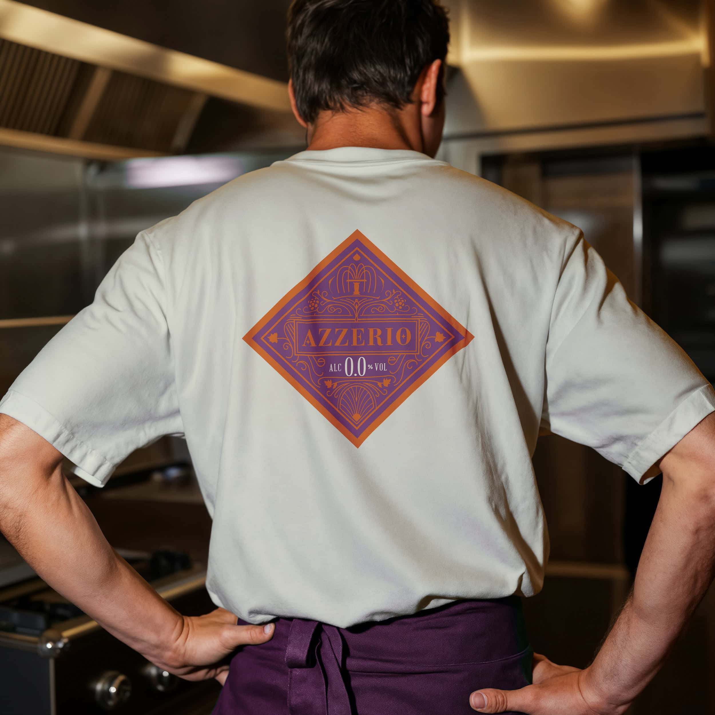 koch in der küche mit azzerio-sujet auf dem rücken seines t-shirts