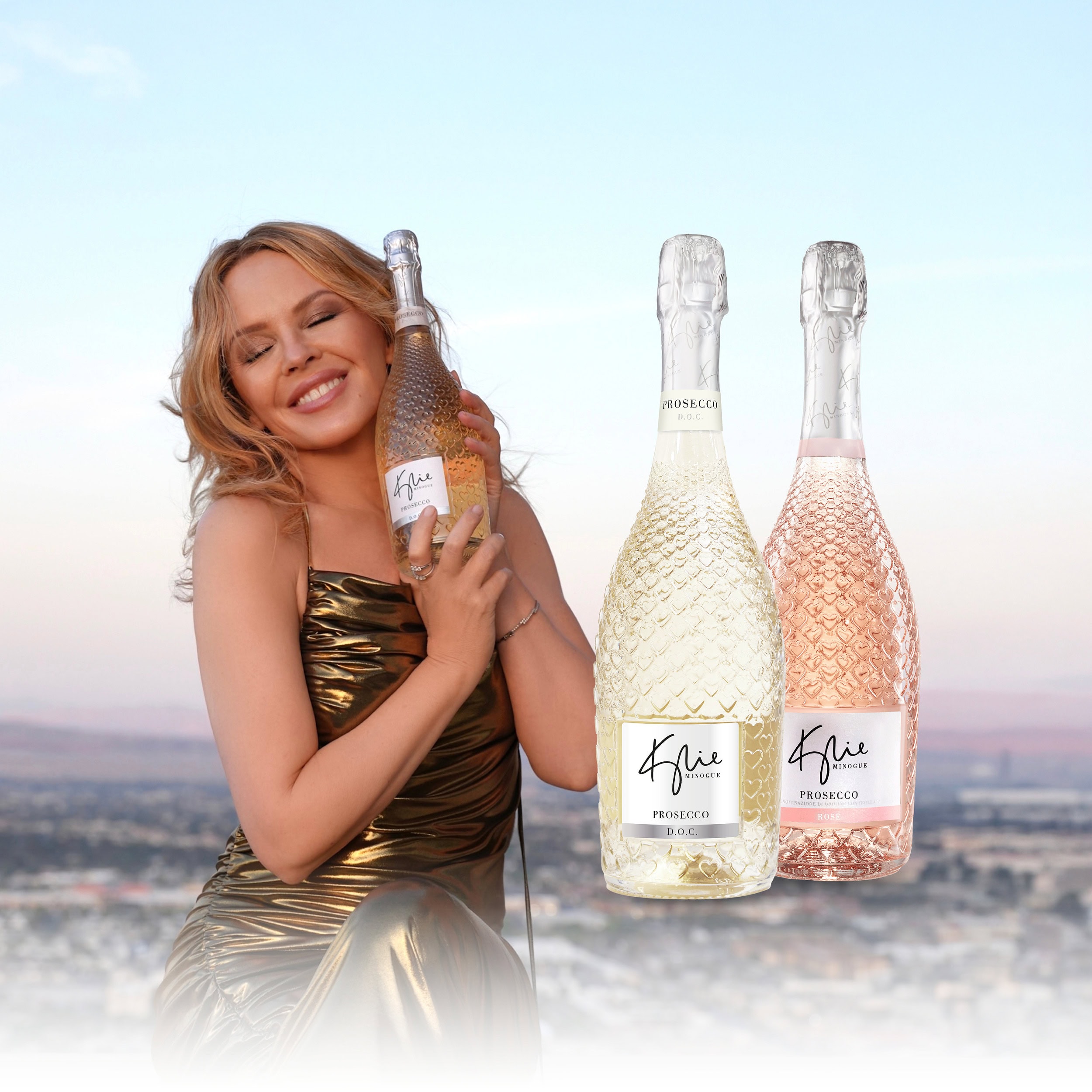kylie minogue mit ihrem prosecco, daneben je eine flasche in weiss und rosé