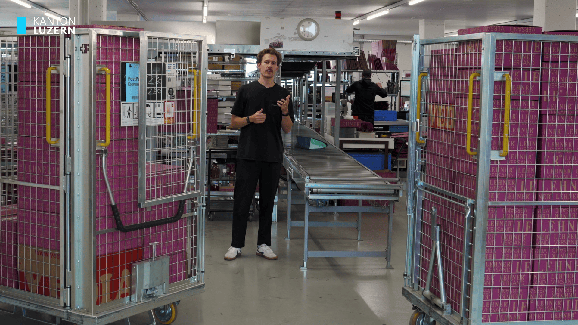 mann in einer lagerhalle zwischen pinken transportboxen