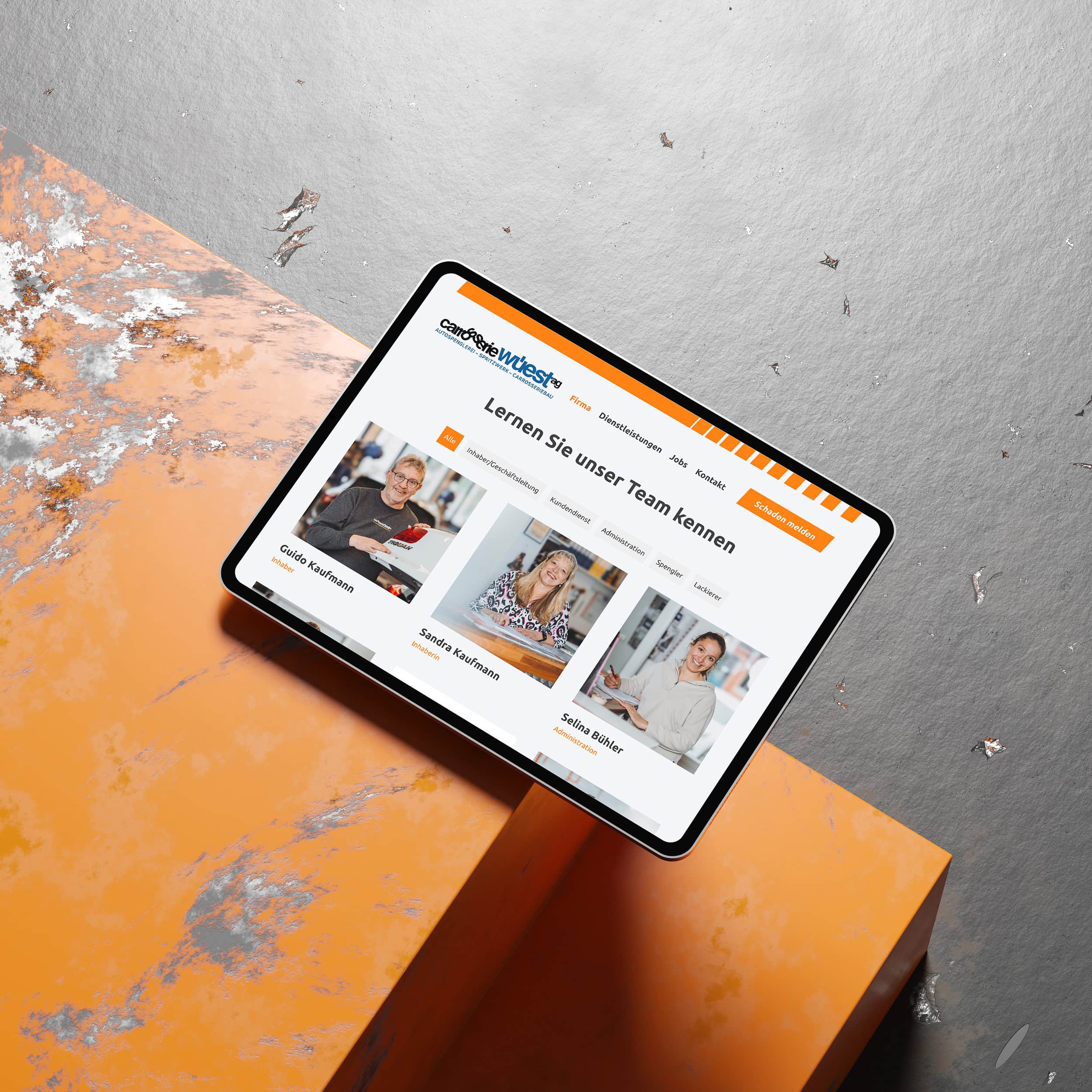 tablet mit der team-seite der carrosserie wüest auf orangem metall