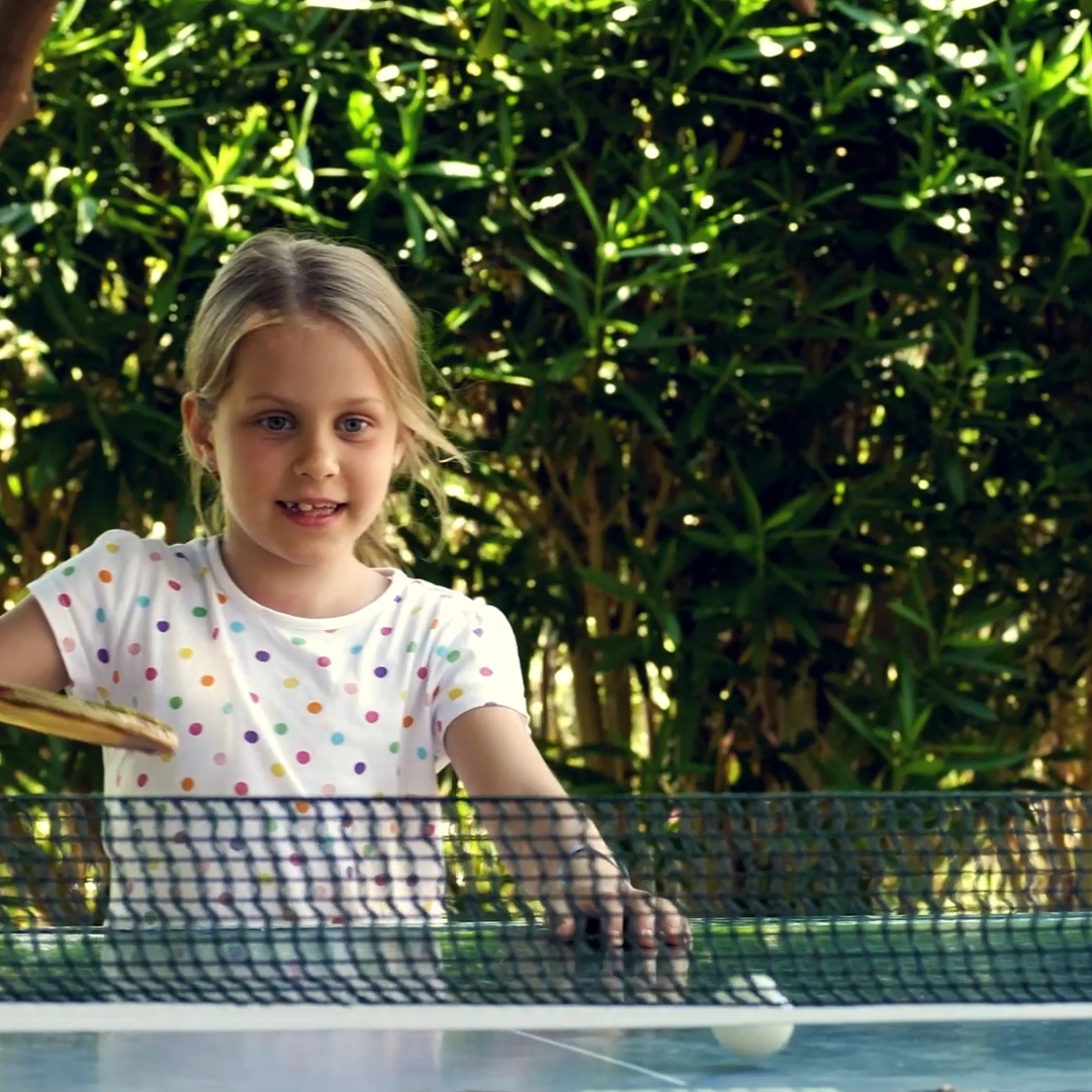 mädchen beim tischtennis im grünen innenhof einer wohnsiedlung
