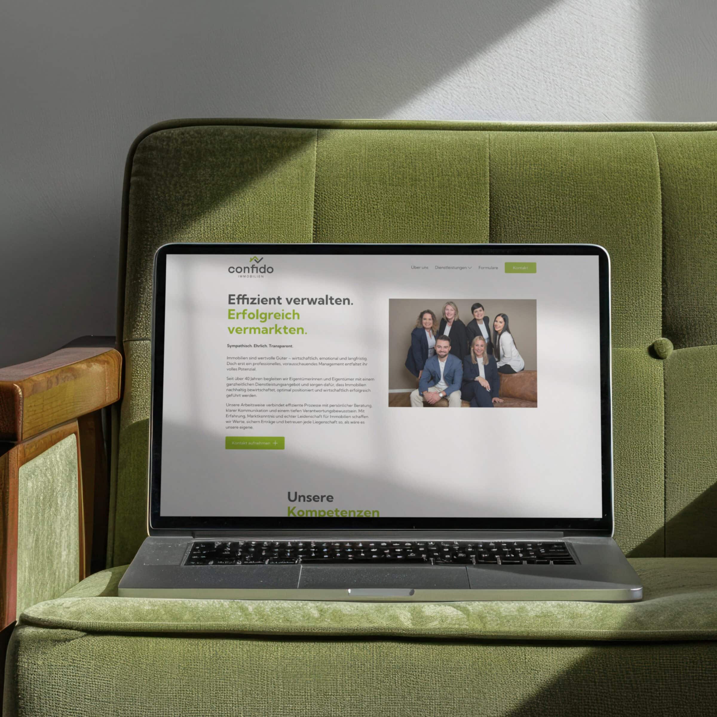 laptop auf einem grünen sessel mit der website von confido immobilien