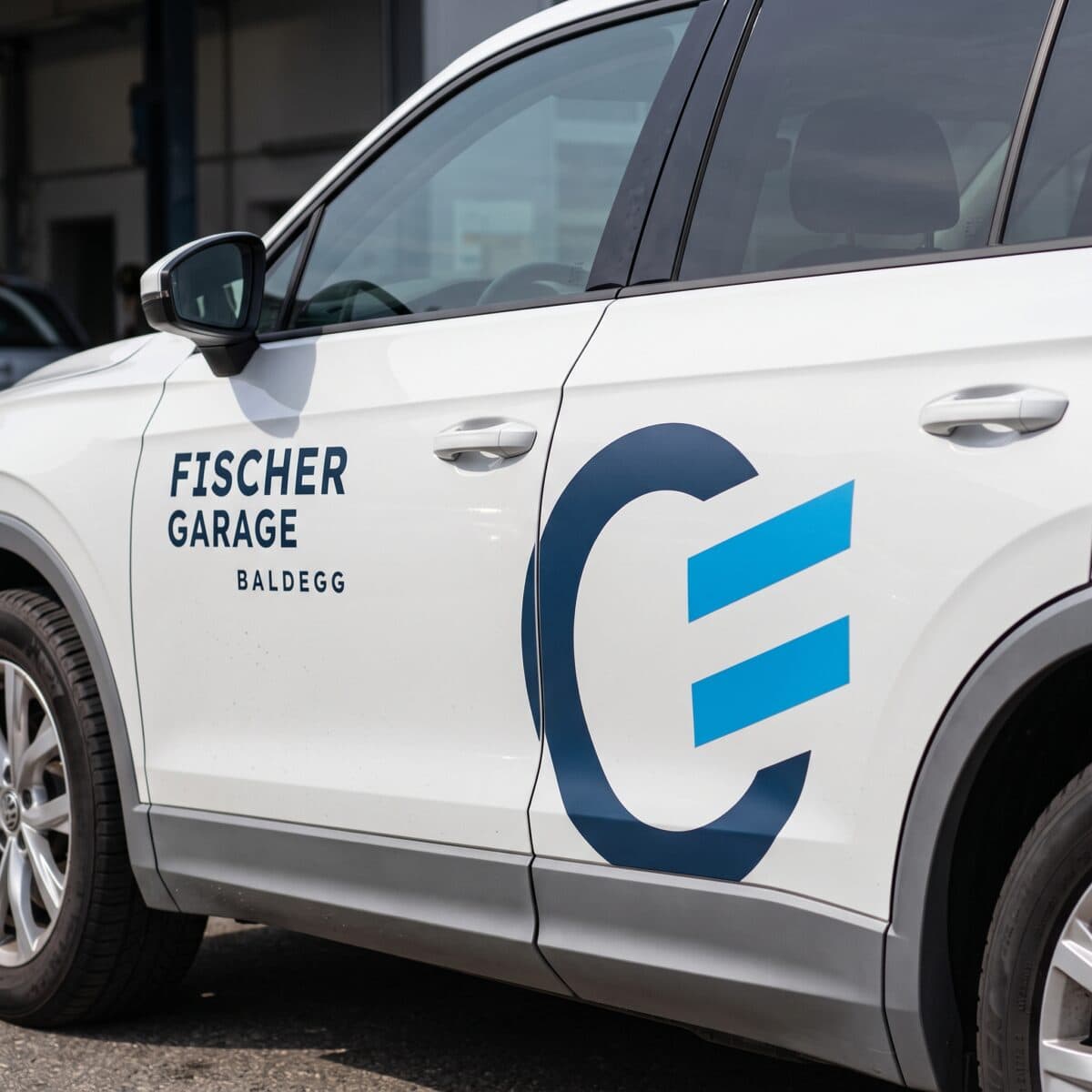 weisses auto mit beschriftung der fischer garage baldegg