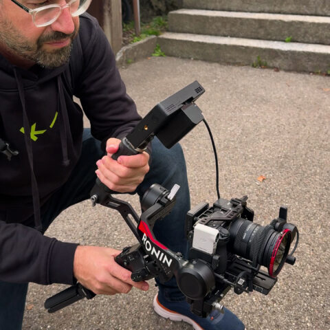 videograf mit gimbal-kamera kniet auf einem platz vor einer treppe