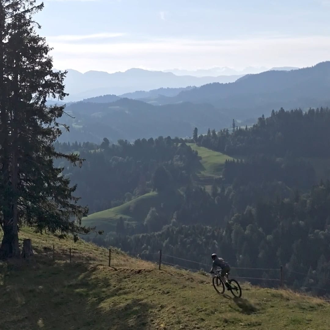 mountainbiker auf einer weide über den bewaldeten hügeln von luthern