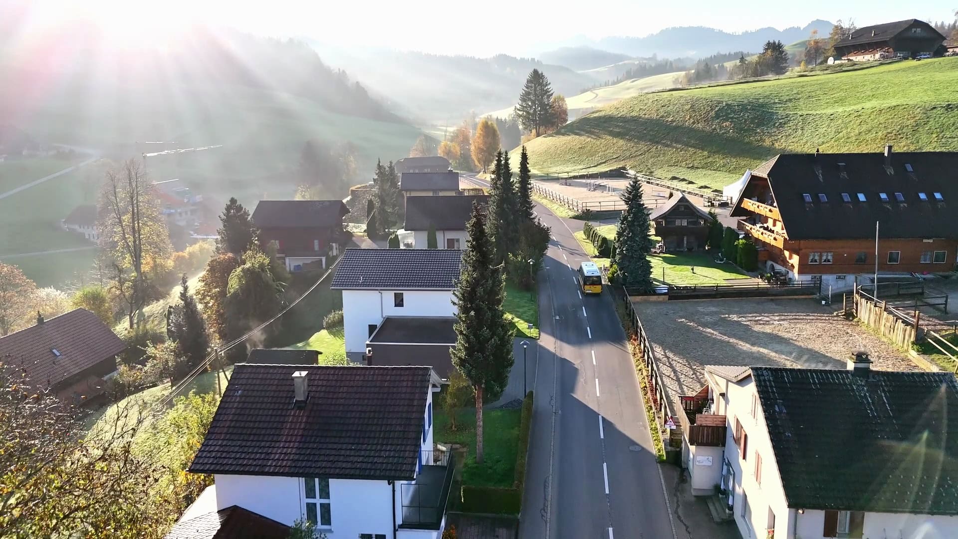 luftaufnahme von luthern mit dorfstrasse und hügeln im gegenlicht