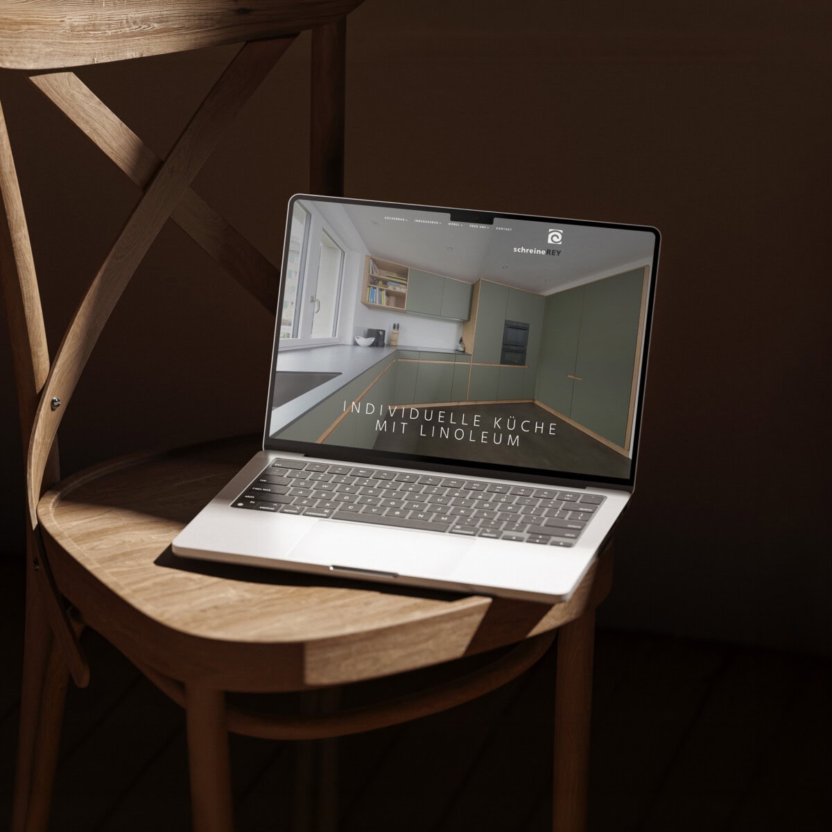 laptop auf einem holzstuhl mit der seite «individuelle küche mit linoleum»