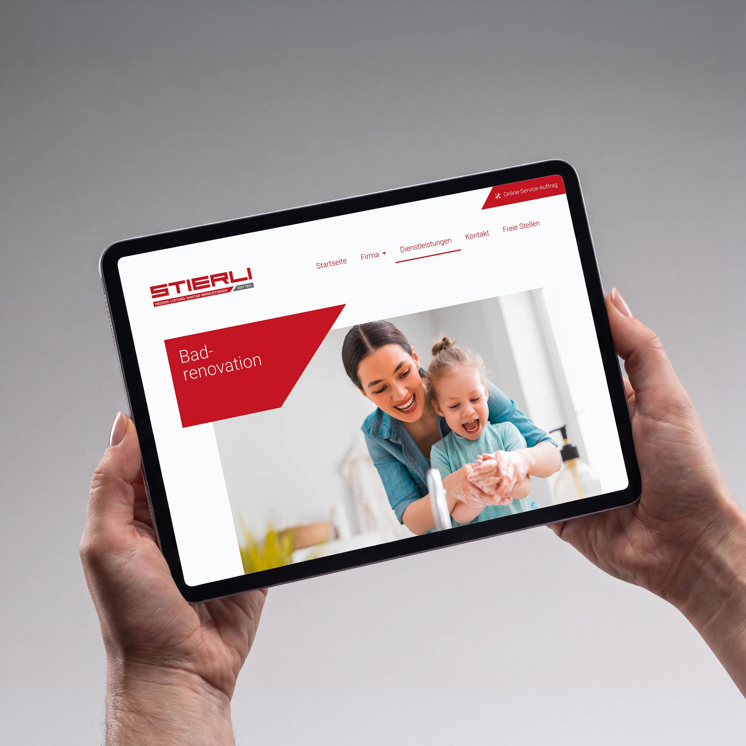 hände halten ein tablet mit der seite «badrenovation» der stierli gmbh
