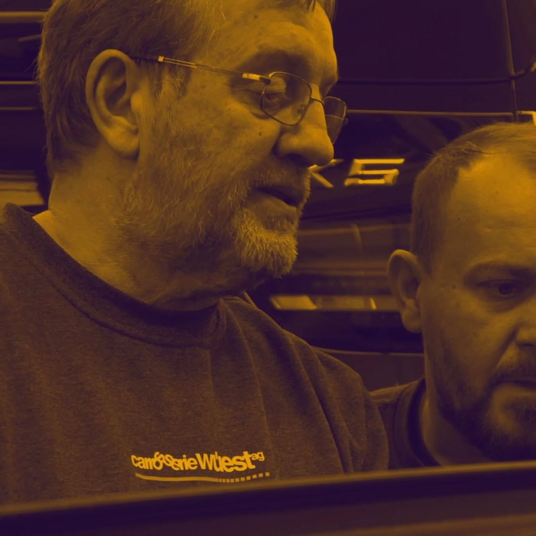 zwei mitarbeiter der carrosserie wüest im gespräch in der werkstatt